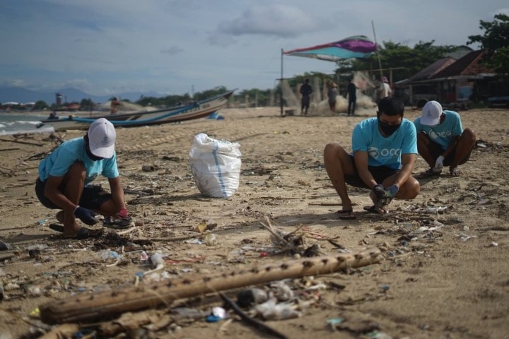 people picking up garbage on a beach